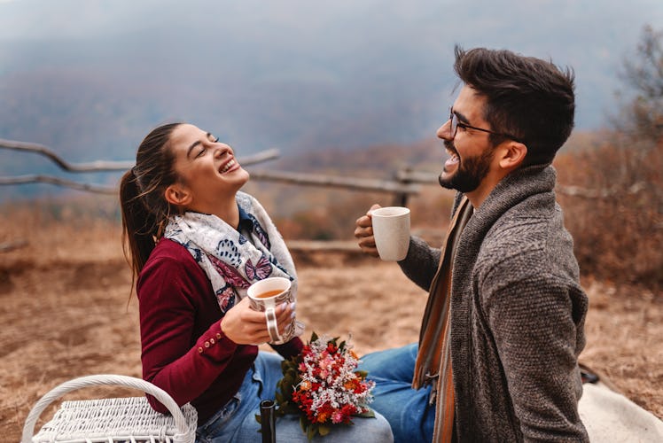 A couple laughs during a Thanksgiving picnic in autumn.