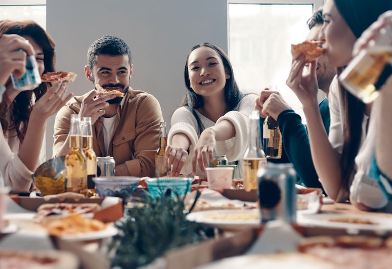 More laugh with friends. Group of young people in casual wear eating pizza and smiling while having ...