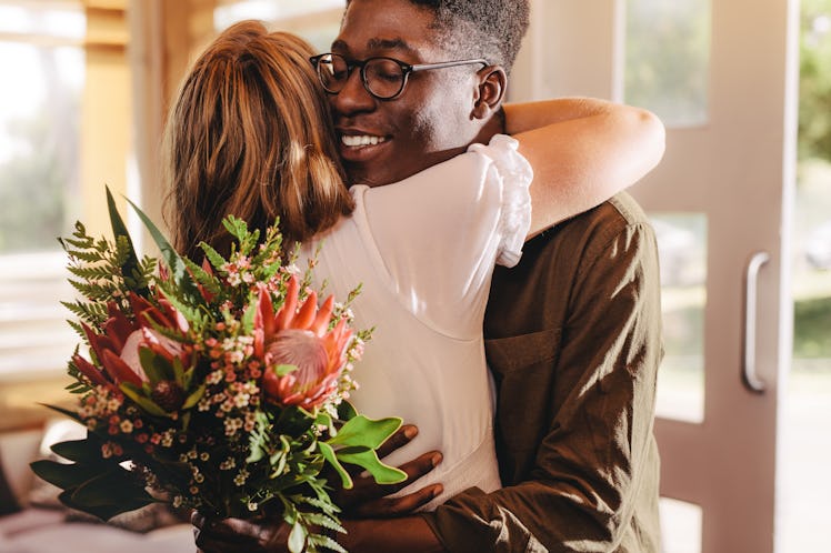 Young african man hugging his girlfriend standing in cafe. Young guy expressing his love for his lad...
