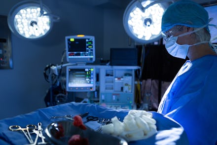 Side view of mature Caucasian male Surgeon performing operation in operation room of hospital