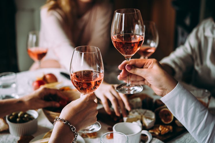 Two girls hold up their glasses of rosé during a Friendsgiving dinner.