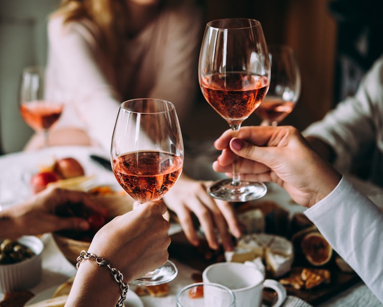Two girls hold up their glasses of rosé during a Friendsgiving dinner.