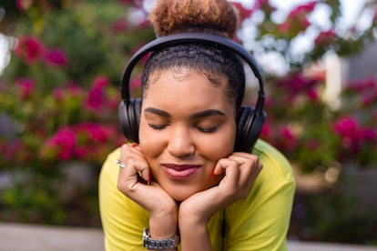 Pretty young black african american woman listening to music with a headphone outdoor