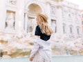A stylish woman poses in front of the Trevi Fountain while studying abroad in Rome.