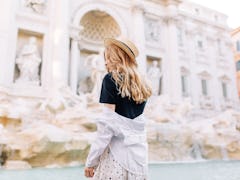 A stylish woman poses in front of the Trevi Fountain while studying abroad in Rome.