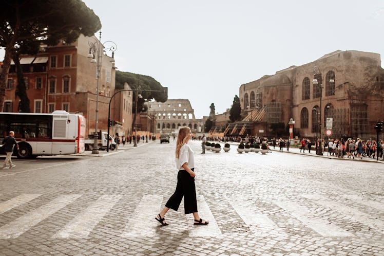 A blonde woman walks on a crosswalk near the Colosseum in Rome while studying abroad.