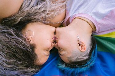 lesbian couple wearing with pride a lgbt flag and kissing lying on the floor.