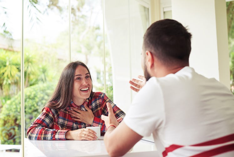 Young man and woman are sitting in bright sunlit room with garden view and vigorously discussing som...