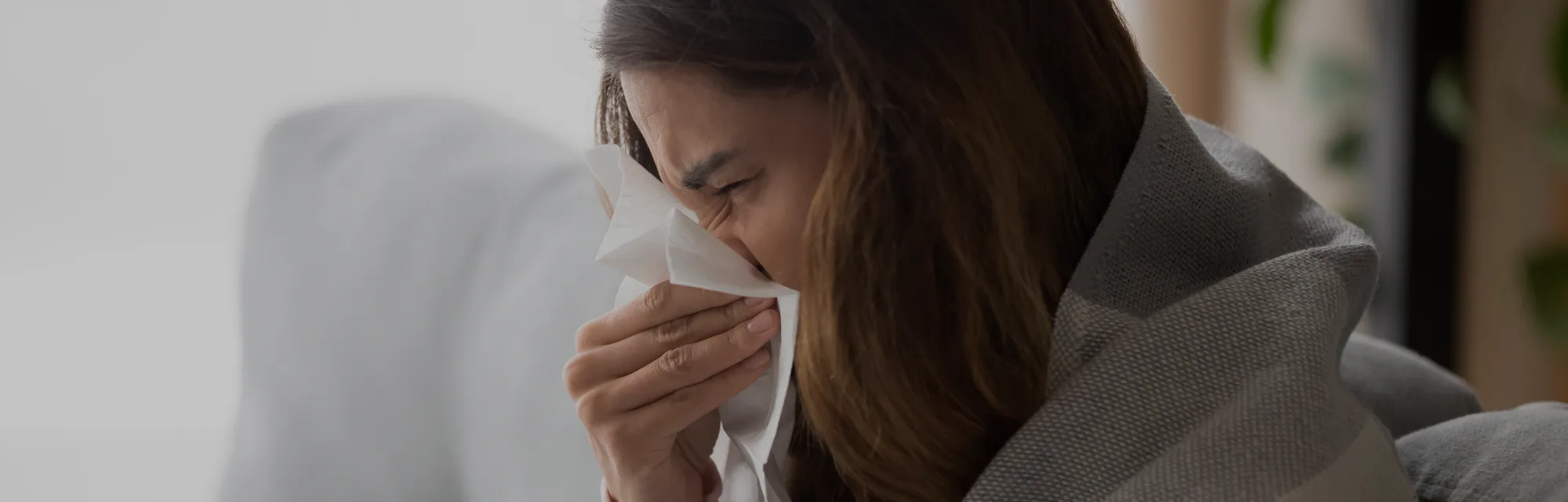 This woman blowing her nose could be staying home from work because of the flu.