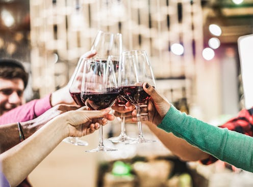 Group of diverse culture friends cheering with red wine in trendy winery bar - Happy people drinking...