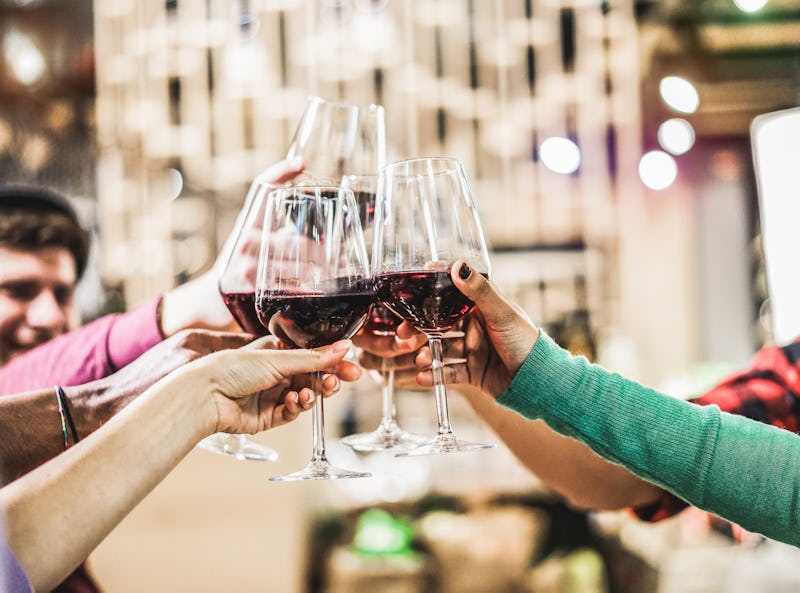 Group of diverse culture friends cheering with red wine in trendy winery bar - Happy people drinking...