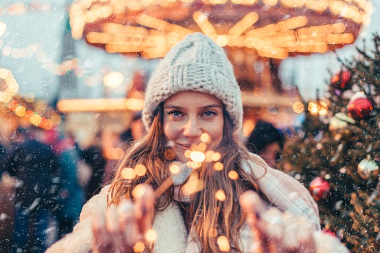 Girl walking in Christmas market decorated with holiday lights in the evening. Feeling happy in big ...