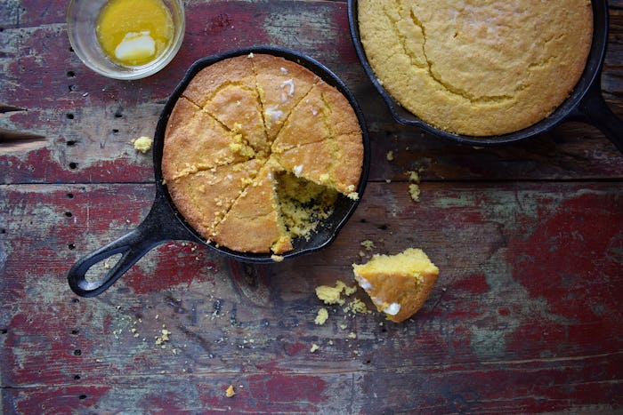 Yellow Cornbread in cast iron skillet on rustic wood table top view