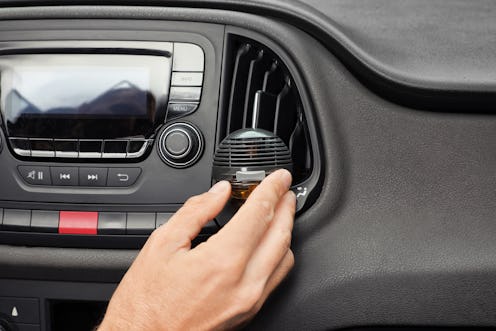 Man regulating air freshener near ventilation in car, closeup