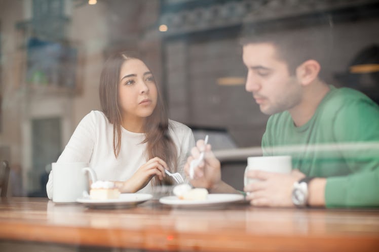 Pretty young brunette talking to her boyfriend in a coffee shop and looking serious