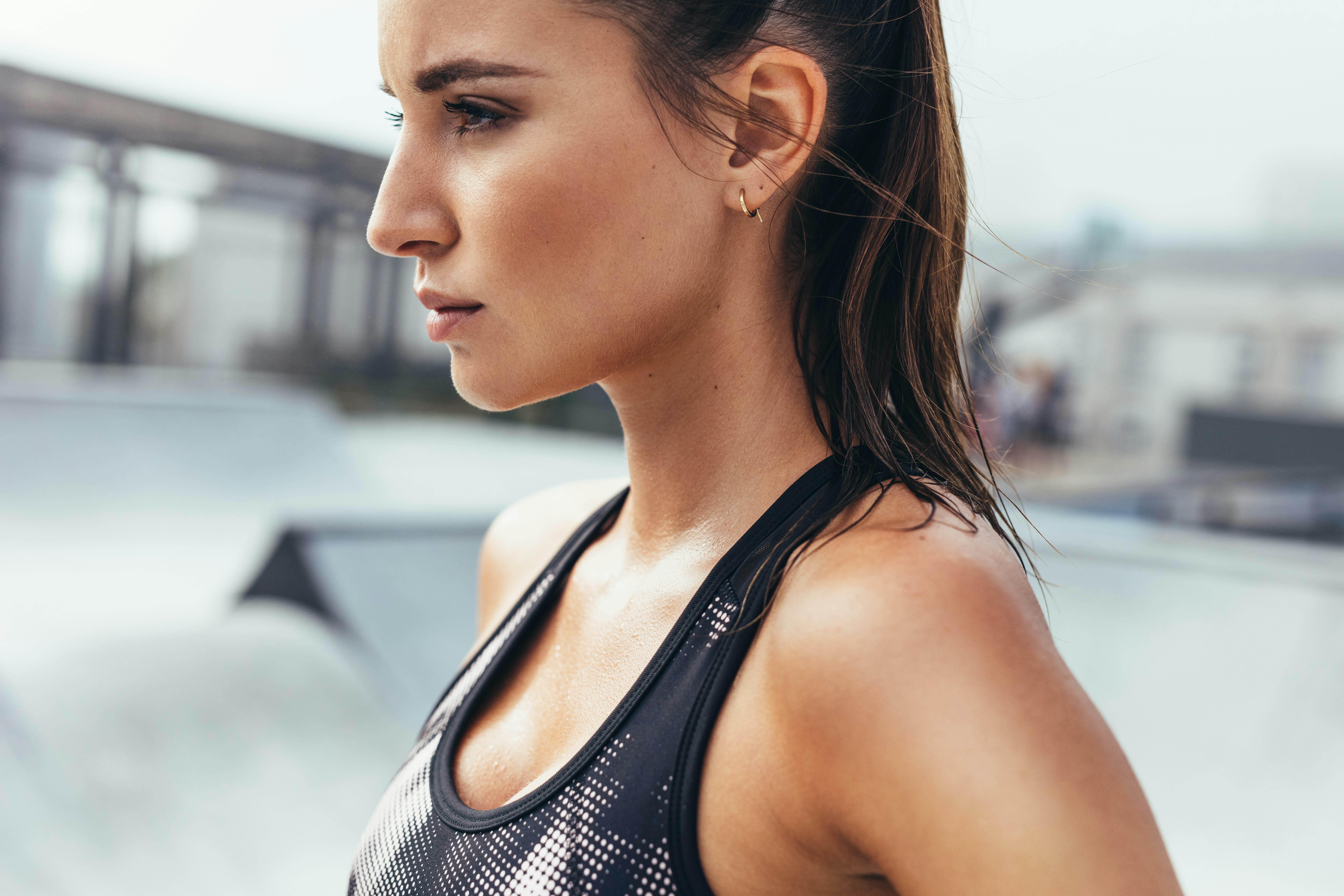 Determined young woman in sportswear standing outdoors. Fit female athlete after workout in morning.