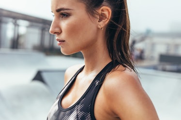 Determined young woman in sportswear standing outdoors. Fit female athlete after workout in morning.