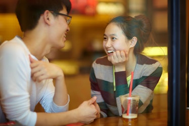 young man and young asian woman dating in cafe