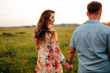 Stylish pregnant couple holding hands on belly in sunny light in summer park. Happy young parents, m...