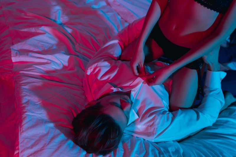cropped shot of woman in underwear sitting on her boyfriend in bed and unbuttoning his shirt