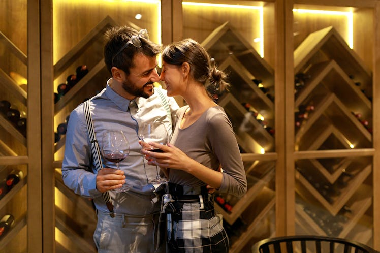 A happy couple on a holiday date taste different wines in a wine cellar.