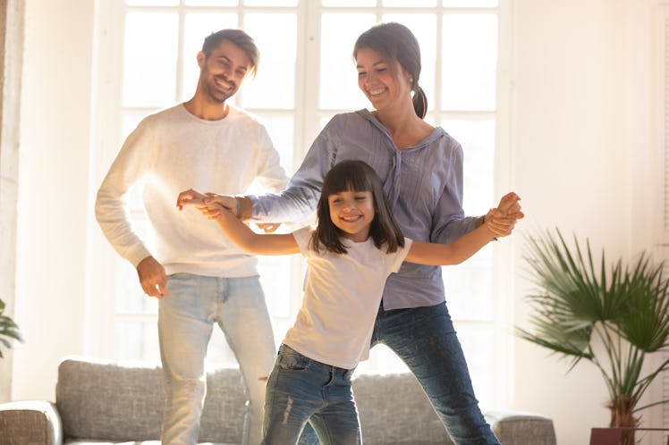 Happy funny family and cute little child daughter laughing dancing in modern living room, joyful par...