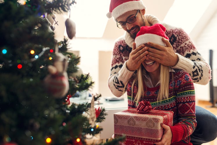  Cropped shot of a man surprising his girlfriend with a Christmas gift.
