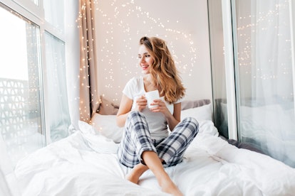 Glamorous girl with happy smile chilling in good morning. Positive female model drinking hot tea.