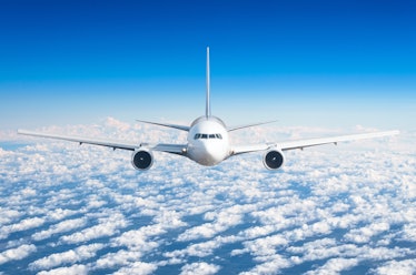 Passenger airplane flying at flight level high in the sky above the clouds and blue sky. View direct...
