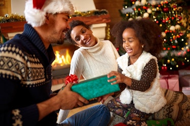 Laughing afro American family in warm Christmas atmosphere exchanging gifts for Christmas