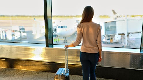 Young woman in the airport looking through the window at airplanes