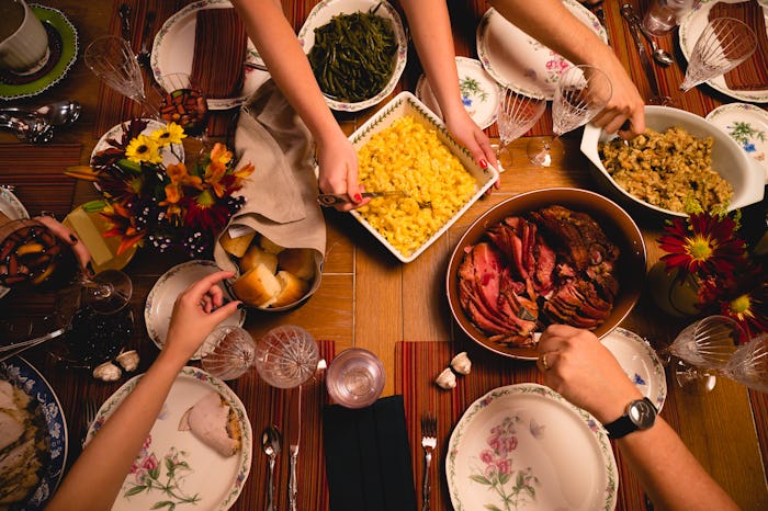 A group of guests sit down for Thanksgiving dinner.