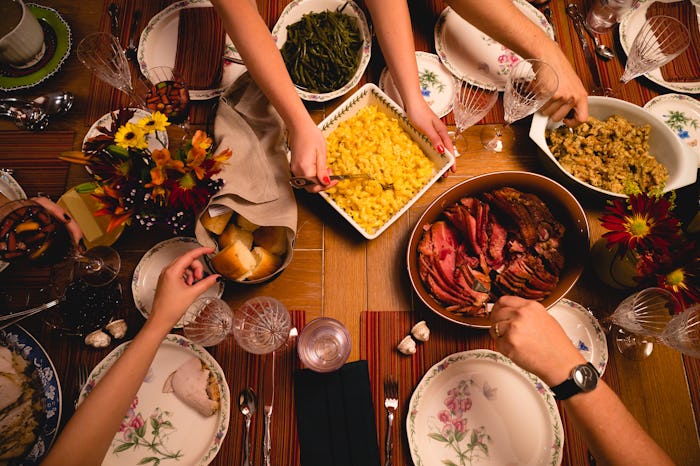 A group of guests sit down for Thanksgiving dinner.