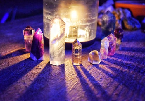 Crystal towers around a candle casting shadows under a full moon.