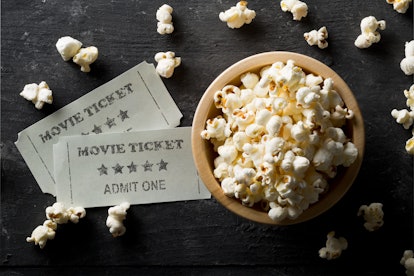 Movie tickets and bowl of popcorn on dark background. Home theatre movie or series night concept. Fl...