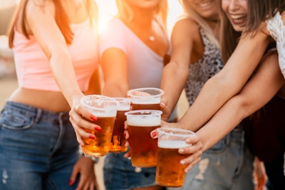 A group of female friends cheers their beer mugs at a brewery.