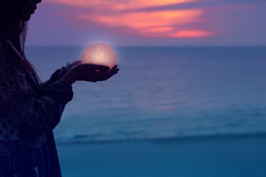 Beautiful attractive girl on a night beach with sand and stars holds the moon in her hands, Artistic...