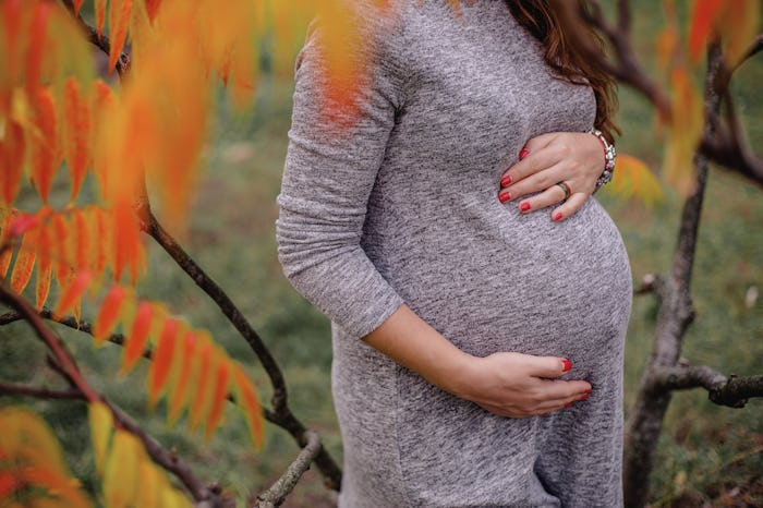a girl hugging her pregnant belly on the 9th month