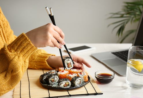 Woman eating tasty sushi rolls at home