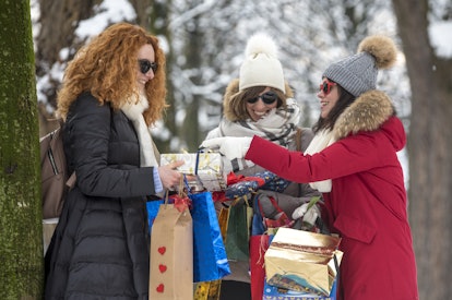 Group of smiling friends celebrate and joke after making winter shopping during Christmas festivitie...