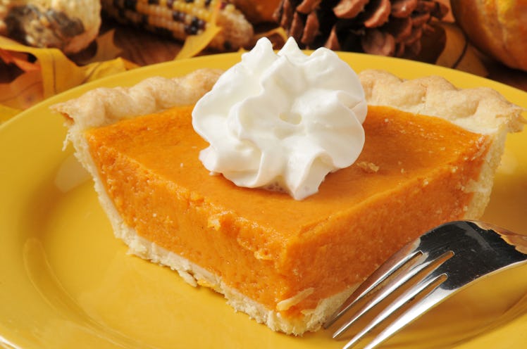 A closeup of a slice of sweet potato pie with whipped cream on top. 