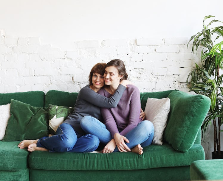 A mother and daughter sit on a green, velvet couch to watch holiday movies.