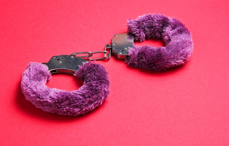 Handcuffs for sex games on red background. Sexual bdsm toy. Fetish, erotic concept.