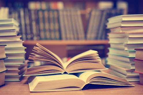 Education learning concept with opening book or textbook in old library, stack piles of literature t...