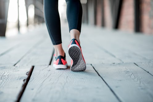 Sports woman in running shoes standing back on the wooden floor, close-up view focused on the sneake...