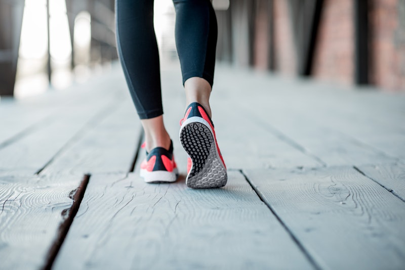 Sports woman in running shoes standing back on the wooden floor, close-up view focused on the sneake...