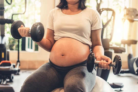 Active pregnant woman exercises in fitness center at yoga room.