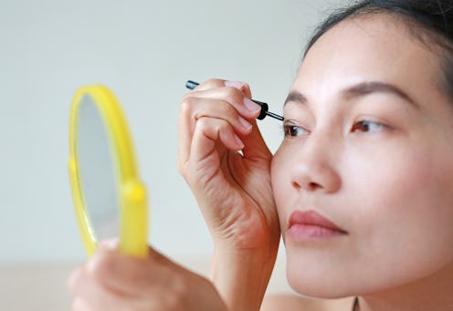 Portrait of beautiful woman making black eyeliner. Beauty Concept.