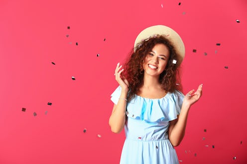 Happy young woman with confetti on color background