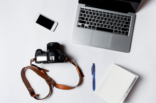 Modern workspace with smartphone, pens, headphone, camera, books and laptop copy space on white colo...
